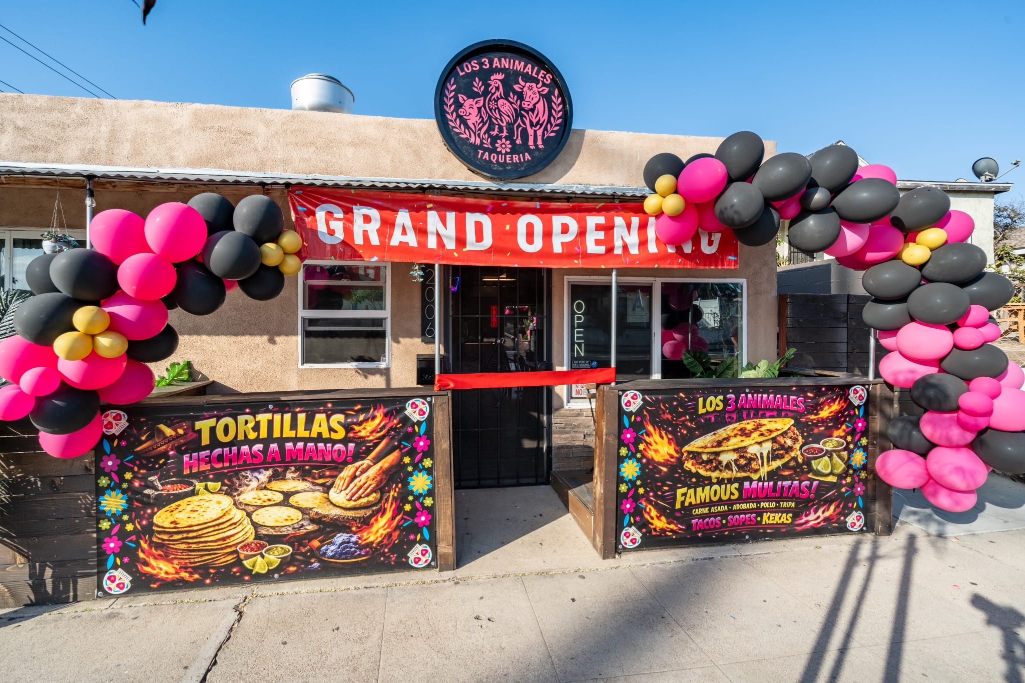 "Grand Opening" banner and balloon arch across the front of Los 3 Animales Taquería